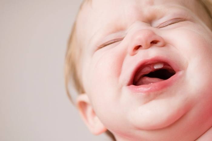 infant in pain from teething symptoms